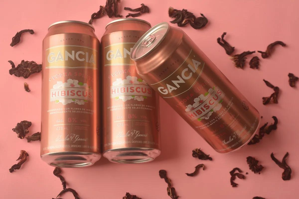 Tres latas de Gancia Hibiscus inclinadas entre flores de hibisco secas